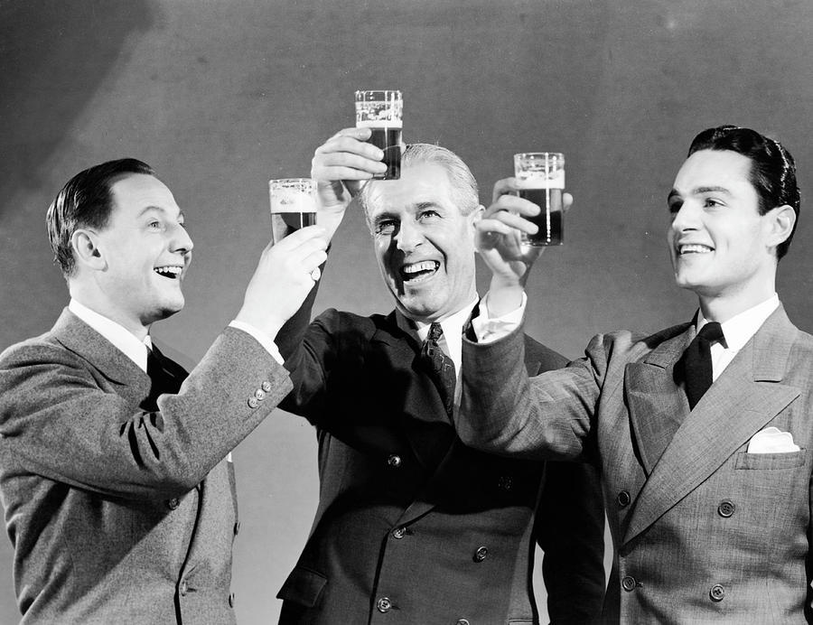 three-men-making-toast-with-glasses-of-beer-bw-hulton-archive
