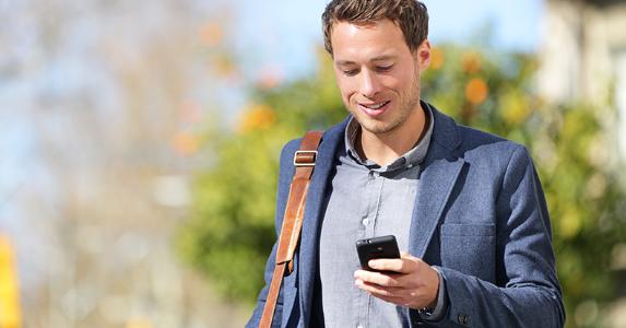 man-with-smartphone-walking-outside-shoulderbag_573x300