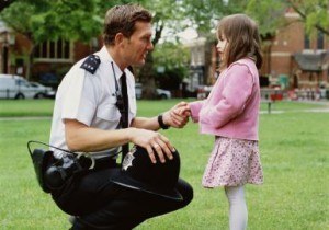 Policeman crouching to talk girl (3-5), outdoors, side view