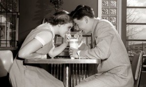 1950s 1960s Laughing Teenage Boy and Girl Sharing Drink Together With Two Straws In Soda Shop