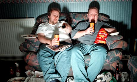 Men lounge on sofa watching TV