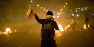 An anti-government demonstrator holds a representation of Venezuela's national flag in front of a burning barricade in the Altamira neighborhood of Caracas, Venezuela, Friday, Feb. 21, 2014. The anti-government movement has appeared to have snowballed into a political crisis, the likes of which Venezuela's socialist leadership hasn't seen since a 2002 coup attempt. Protest rallies are expected throughout the country on Saturday. (AP Photo/Rodrigo Abd)