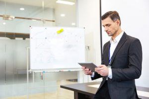 Focused businessman standing and using tablet in office