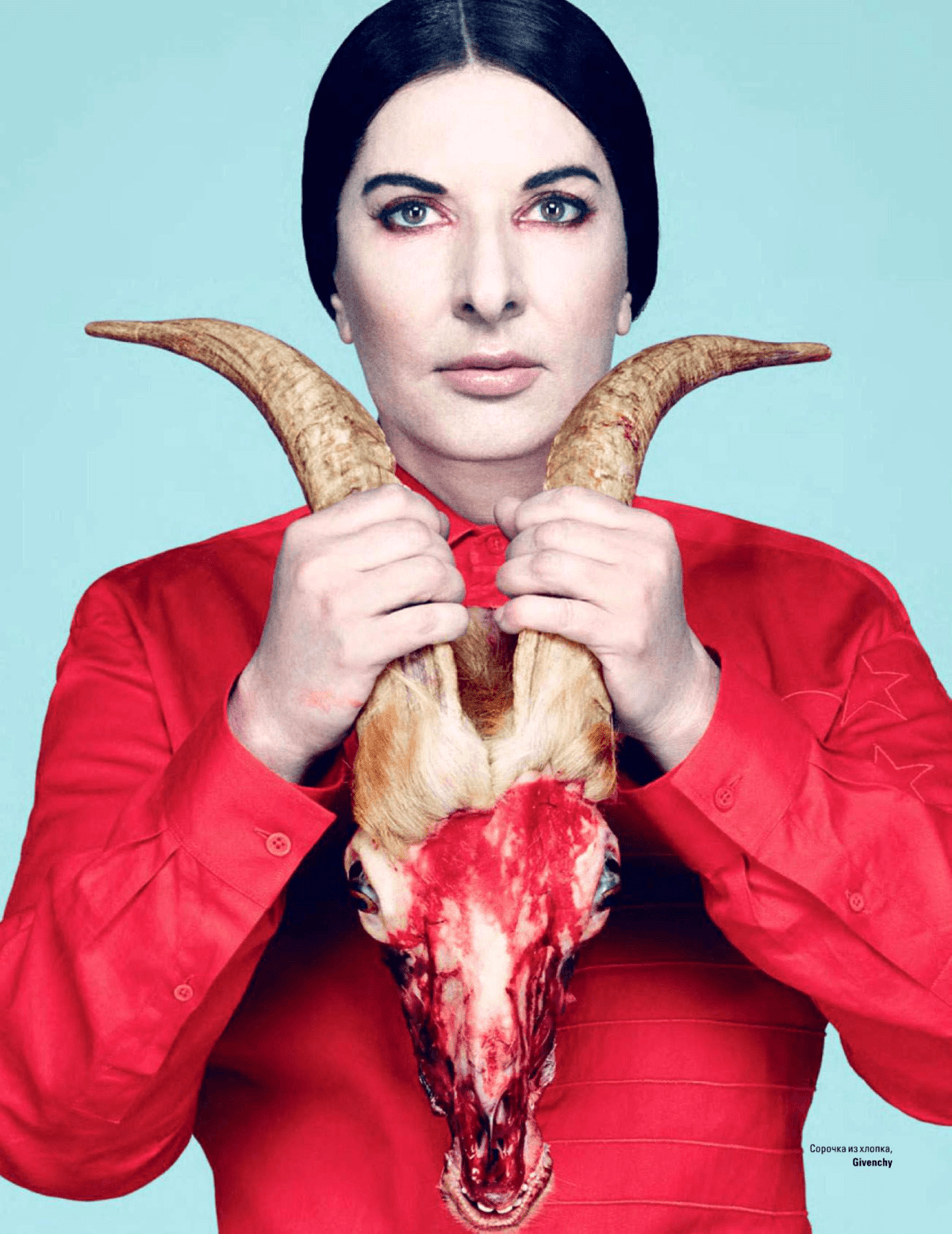 Holding the skinned head of a dead goat, a clear reference to the occult character Baphomet