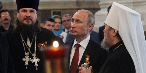 SEVASTOPOL, CRIMEA - MAY 9: Russian President Vladimir Putin (C) listens to Russian Orthodox Church priests in Vladimir Cathedral May 9, 2014 in Sevastopol, a city in the Crimean Peninsula whose status is under dispute between Russia and Ukraine. Putin was visiting the disputed area for the first time since its annexation from Ukraine by Russia. (Photo by Sasha Mordovets/Getty Images)